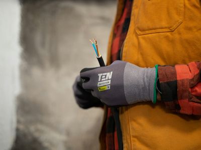 Electrician in work gloves holding stripped electrical wires